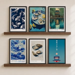 May include: Six framed art prints arranged on two wooden shelves. The prints feature various illustrations including koi fish, oysters on ice with lemon, a traditional building by water, ocean waves, oysters with calligraphy, and a temple under a moon.
