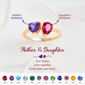May include: A gold-toned ring featuring an open design with a purple heart-shaped gemstone and a pink pear-shaped gemstone. Text reads: Mother & Daughter, Our hearts stick together in the ebbs and flows, Mother's Birthstone, Daughter's Birthstone.