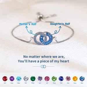 May include: Silver bracelet with two interlocking circles, one with blue crystals and the other with blue baguette crystals. Text reads "Mother's Half" and "Daughter's Half". The text "No matter where we are, You'll have a piece of my heart" is also present.