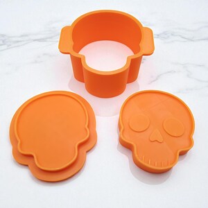 May include: Orange silicone skull-shaped cookie cutters and mold. The set includes a skull-shaped mold, a skull-shaped cutter, and a skull-shaped stamp. Perfect for Halloween-themed baking and crafting projects.
