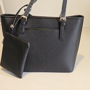 May include: Black tote bag with a matching small pouch. The bag has two top handles and a detachable shoulder strap. Gold-colored hardware accents the bag's design. The bag is made of a textured material.