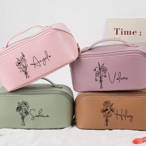 May include: Four personalized cosmetic bags in pink, lavender, sage green, and tan. Each bag has a floral design and a name in script: Angela, Valerie, Sabrina, and Hilary. The bags have a handle and a zipper closure.