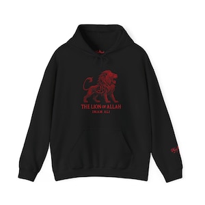 Puede incluir: Sudadera con capucha negra con un gráfico de león rojo y el texto "THE LION OF ALLAH IMAM ALI". La sudadera tiene un bolsillo de canguro y una capucha con cordón. Un pequeño diseño rojo está en la manga.