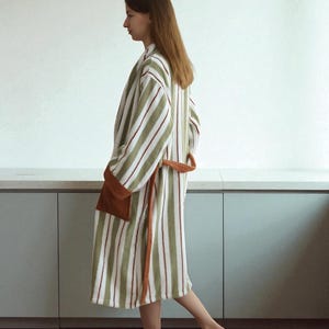 May include: A striped robe in shades of green, white, and burgundy. The robe features a brown pocket and a matching belt. The robe is made of a soft, absorbent material, perfect for after a shower or a relaxing day at home.