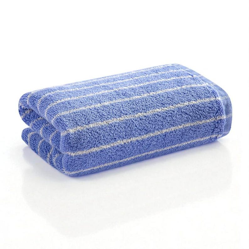 May include: Folded blue bath towel with white stripes. The towel is made of a soft, absorbent material and is folded neatly. The stripes run horizontally across the towel.