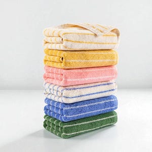 May include: A stack of seven folded towels in various colors: cream with yellow stripes, yellow, pink, white with blue stripes, blue, and green. The towels are neatly arranged, showcasing a range of hues and striped patterns. The towels are made of a soft, absorbent material.
