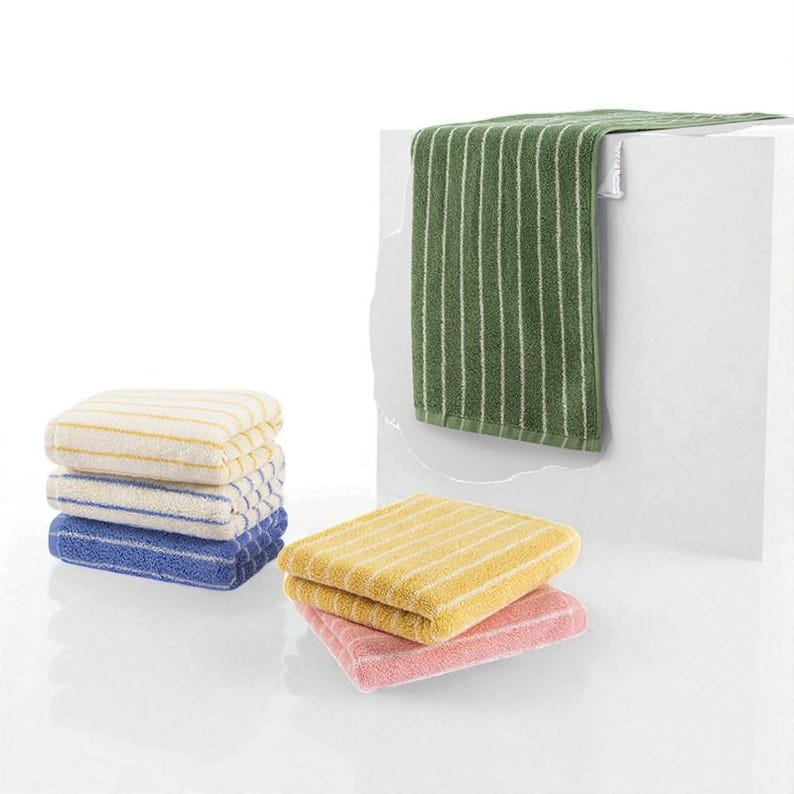 May include: A collection of striped towels in various colors, including green, yellow, pink, blue, and cream. The towels are stacked and folded, with one green towel hanging. The towels have white stripes.