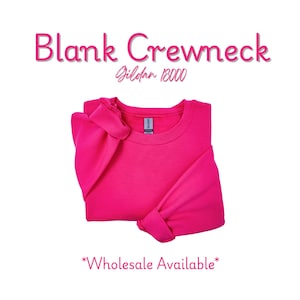 May include: A bright pink crewneck sweatshirt, folded neatly. The text "Blank Crewneck" is above the sweatshirt, with "Gildan 18000" below it. The words "Wholesale Available" are at the bottom. The sweatshirt is a solid color.