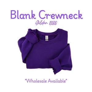 Puede incluir: Una sudadera de cuello redondo morada oscura doblada. El texto "Blank Crewneck" est&aacute; encima de la sudadera, con "Gildan 18000" debajo. Las palabras "Wholesale Available" est&aacute;n en la parte inferior de la imagen.