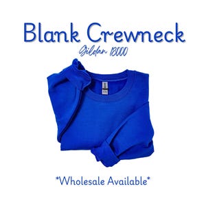 May include: A royal blue crewneck sweatshirt, folded on a white background. The text "Blank Crewneck" is above the sweatshirt, with "Gildan 18000" below it. The words "Wholesale Available" are at the bottom.