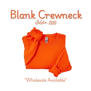 May include: Bright orange crewneck sweatshirt, folded neatly. The text "Blank Crewneck" and "Gildan 18000" are displayed above the sweatshirt. The words "Wholesale Available" are at the bottom.