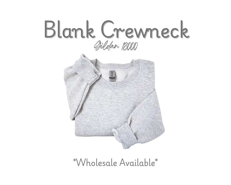 K&ouml;nnte beinhalten: Ein hellgraues, leeres Crewneck-Sweatshirt, ordentlich gefaltet. Der Text "Blank Crewneck" steht &uuml;ber dem Sweatshirt, darunter "Gildan 18000". Die Worte "Wholesale Available" stehen unten.
