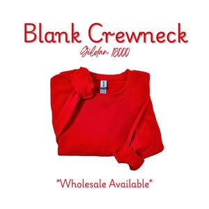 May include: A bright red crewneck sweatshirt, folded neatly on a white background. The text "Blank Crewneck" is displayed in red, with "Gildan 18000" below it. The words "Wholesale Available" are at the bottom.