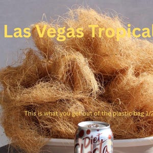 May include: A large pile of brown, fibrous material, possibly coconut coir, fills the frame. The text "Las Vegas Tropicals" is at the top. A Diet Cola can sits in a white pot in front of the pile. Text reads "This is what you get out of the plastic bag 1/2 lb."