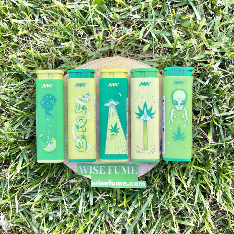May include: Five green and yellow cylindrical containers with various designs, including a guitar, the number 420, an alien with a cannabis leaf, a rocket with a cannabis leaf, and an alien. The containers are arranged on a wooden surface, with the text "WISE FUME" and "wisefume.com" visible.