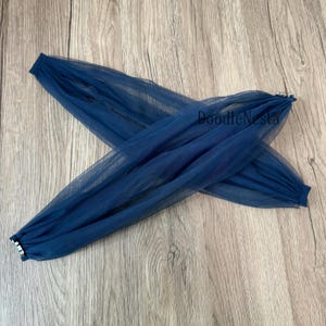 Puede incluir: Mangas de tul azul marino, fruncidas en los extremos, cruzadas sobre una superficie de madera. El texto "DoodleNesta" es visible en el tul. Las mangas están hechas de una tela ligera y transparente.