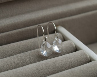 May include: A pair of silver dangle earrings with clear crystal teardrop-shaped stones.
