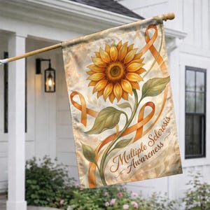May include: A garden flag featuring a large sunflower with orange ribbons and the words "Multiple Sclerosis Awareness." The flag has a beige background with a floral design and is hanging on a wooden pole.