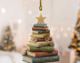 May include: A Christmas tree ornament shaped like a stack of books, topped with a star. The books are various colors, including blue, green, and red, with floral designs. The word "Name" is written on the bottom book.