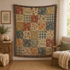 May include: A woven throw blanket featuring a patchwork design of alternating squares. The pattern includes various floral prints in shades of red, blue, and tan, interspersed with blue and white gingham checks. The edges are finished with fringe.
