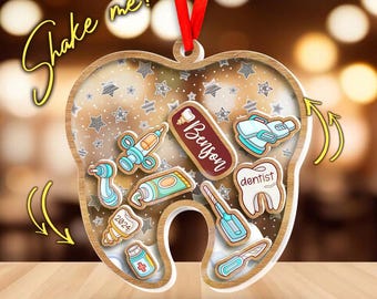 May include: A tooth-shaped ornament with a wooden frame and a red ribbon for hanging. Inside, various dentist-themed illustrations and the name "Benson" are visible. The text "Shake me!" is written in a cursive font.