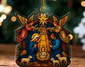 May include: A Christmas ornament featuring a stained-glass style Nativity scene. The ornament depicts Mary, Joseph, and baby Jesus, with angels and lambs. The text "Custom name year" is written across the top. The ornament is hanging by a gold string.