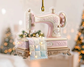 May include: A pink and cream-colored sewing machine ornament with floral details and the name "Alice". The ornament features a miniature quilt and is adorned with small lights and greenery. The base has the year "1915" engraved.