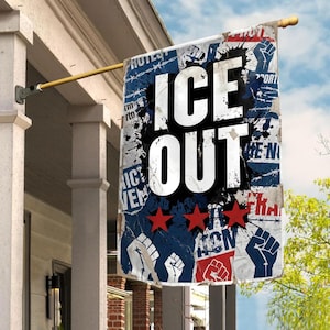 May include: A rectangular flag with the words "ICE OUT" in large white letters, set against a blue and black background with red stars and fist graphics. The flag is hanging from a gold-colored pole.
