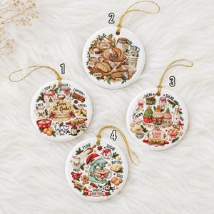 Pu&ograve; includere: Quattro ornamenti rotondi in ceramica bianca con cordini dorati. Ognuno presenta illustrazioni colorate a tema pasticceria, inclusi ingredienti come farina, zucchero e latte, con testi come Born To Bake e Name 2026, numerati da 1 a 4.