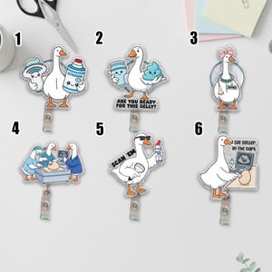 May include: Six acrylic badge reels featuring cartoon geese in medical settings. Designs include geese with ultrasound equipment, a goose with a pink bow and stethoscope, a goose wearing sunglasses with the text SCAN EM, and a goose with a laptop.