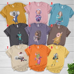 May include: A collection of nine colorful t-shirts, each featuring a character from the animated movie "Sing." The shirts are in various colors, including yellow, pink, blue, and gray, with different character designs printed on the front.