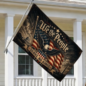 May include: A rectangular flag featuring the American flag with an eagle and the text "We the People" and "Serve No Kings." The flag is dark with a vintage design and is hanging on a white pole.
