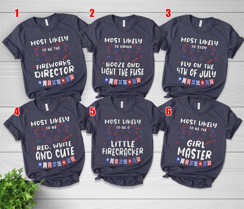 May include: Six navy blue t-shirts with white text and red, white, and blue graphics. The shirts have phrases like "Most Likely to be the Fireworks Director" and "Most Likely to be a Little Firecracker."