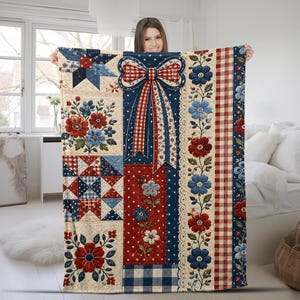 May include: A rectangular quilt featuring a patchwork design with red, white, and blue colors. The pattern includes floral motifs, a large central bow, checkered stripes, and star shapes. The fabric has a quilted texture with visible stitching lines.