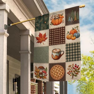 May include: A rectangular garden flag featuring a patchwork design with autumn-themed illustrations including a bear in a pumpkin, pine trees, maple leaves, pumpkins, a mug of coffee, mushrooms, a lattice-top pie, and berries on a gold metal pole.
