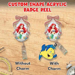 Puede incluir: Dos portatarjetas de acr&iacute;lico con forma personalizada que muestran una sirena pelirroja en un marco floral con un lazo rosa. Uno es simple, el otro incluye un dije de pez amarillo y azul. Texto: CUSTOM SHAPE ACRYLIC BADGE REEL, WITHOUT CHARM, WITH CHARM.