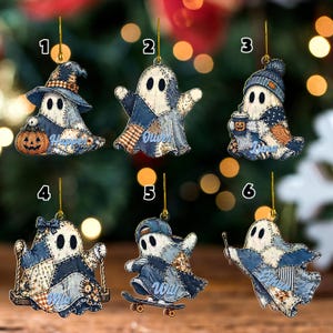 May include: Six hanging ornaments featuring ghost characters with a blue patchwork quilt pattern. Each ghost has a unique accessory: a witch hat and pumpkin, a plain ghost, a beanie and coffee cup, a swing, a skateboard, or a wand. Names are printed on each.