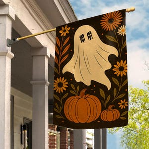 May include: A rectangular garden flag featuring a black background with a central cream-colored ghost graphic displaying the text FOT FOT. The design includes orange and yellow flowers on stems and two orange pumpkins at the bottom of the flag.