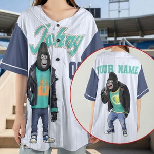 May include: A white baseball jersey with thin vertical stripes and dark blue sleeves. The front features a graphic of a gorilla in a leather jacket and the text Johny. The back, shown in a circular inset, displays the text YOUR NAME above a gorilla.