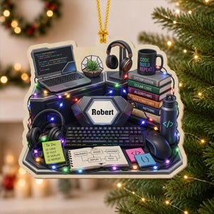 May include: A decorative ornament featuring a computer desk setup with a laptop, keyboard, mouse, headphones, a stack of books labeled System Design, Clean Code, Algorithms, Data Structures, and Patterns, a water bottle, and a notebook with the name Robert.