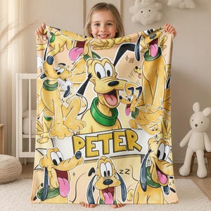 May include: A beige blanket featuring a repeating pattern of a cartoon dog with a green collar and black ears. The dog is in various poses with its tongue out. The name "PETER" is printed on a banner.