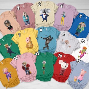 May include: A collection of fifteen colorful t-shirts, each featuring a different cartoon character from the movie "Sing". The shirts are in various colors, including pink, blue, green, yellow, and red. Each shirt has a unique design.