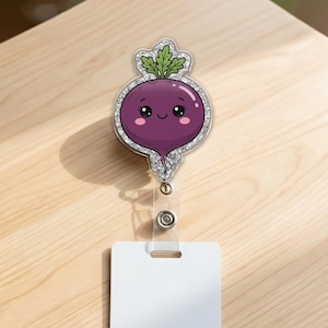 May include: A purple beet-shaped badge reel with a smiling face and green leaves. The badge reel has a glittery silver border and a clear plastic retractable cord with a white card holder.