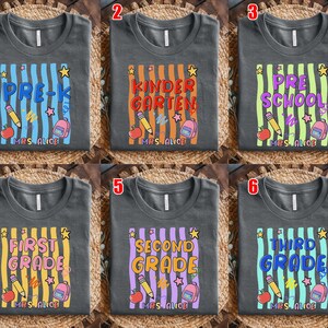 May include: Gray t-shirts with colorful vertical stripes and school-themed graphics. Each shirt features a different grade level: Pre-K, Kindergarten, Preschool, First Grade, Second Grade, and Third Grade. Includes pencils, apples, stars, and backpacks.