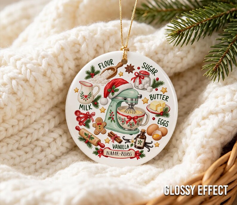 Pu&ograve; includere: Un ornamento rotondo in ceramica bianca a tema pasticceria festiva, con una planetaria verde menta che indossa un cappello da Babbo Natale, circondata da illustrazioni di farina, zucchero, latte, burro, uova, vaniglia e un omino di pan di zenzero.
