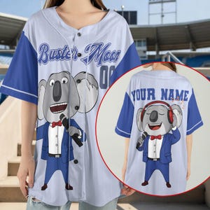 May include: A light blue and white pinstriped baseball jersey featuring a graphic of Buster Moon in a blue suit on the front with the text Buster Moon. The back view shows a koala wearing headphones and a suit with the text YOUR NAME.