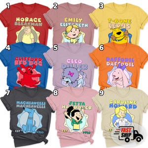 May include: A collection of nine colorful t-shirts, each featuring a cartoon character's name and image. The shirts are in various colors, including red, blue, yellow, orange, and gray. The designs include characters like Clifford, T-Bone, and Emily.