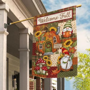 May include: A rectangular garden flag featuring the text Welcome Fall, a pumpkin-shaped house, two gnomes, sunflowers, red and white spotted mushrooms, and autumn leaves. The design is set against a patchwork background of plaid and floral patterns.