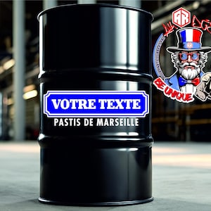 Op de afbeelding: Een zwarte metalen trommel met een blauw rechthoekig label met de witte tekst VOTRE TEXTE en de witte tekst PASTIS DE MARSEILLE eronder. Een cirkelvormig logo met een bebaard personage met een hoge hoed bevindt zich rechtsboven.