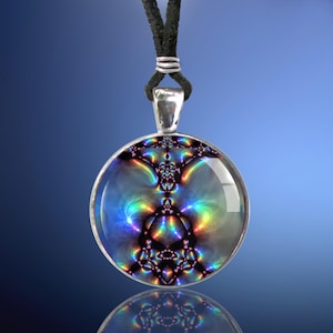 May include: A silver pendant necklace with a round, iridescent glass charm featuring a colorful, abstract design. The charm has a black background with a rainbow-like pattern.